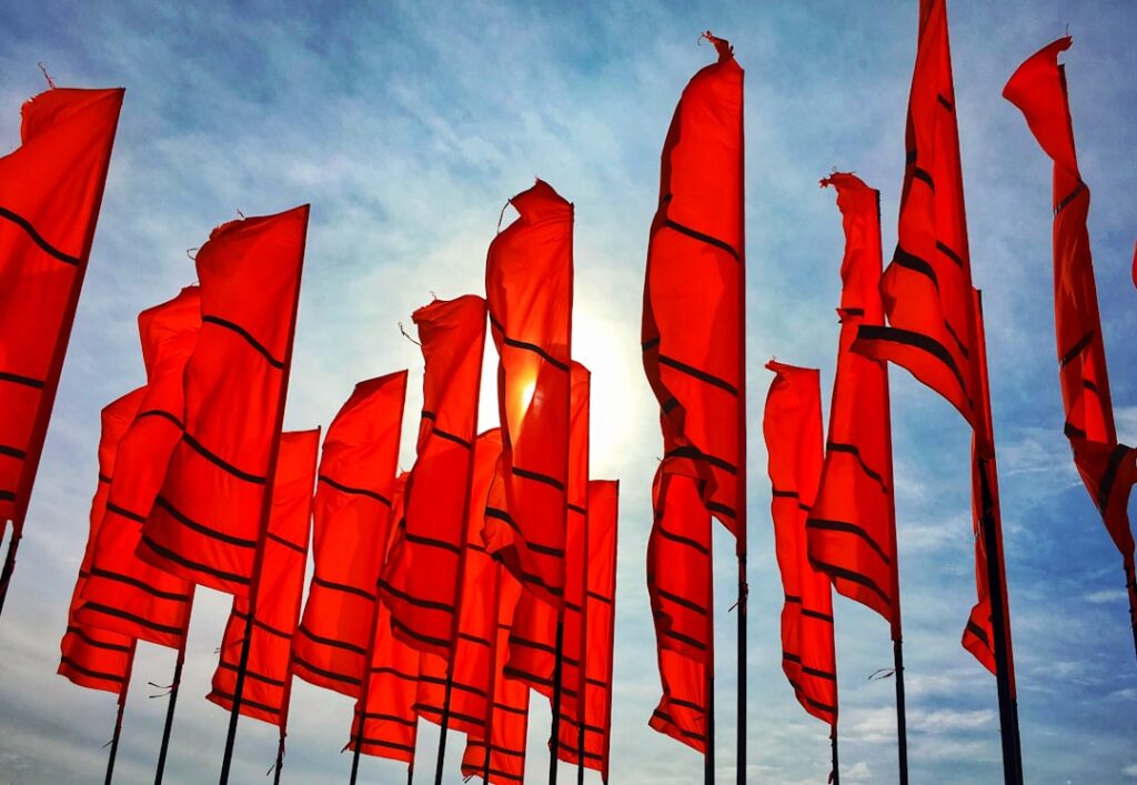 Red flags waving in strong winds as warning signs