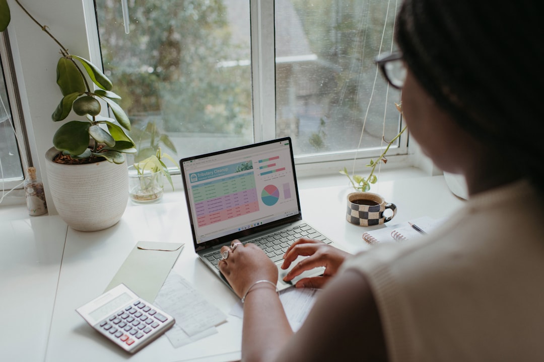 Small business owner analyzing budget data on laptop with calculator for SEO pricing decisions. Photo by Unsplash