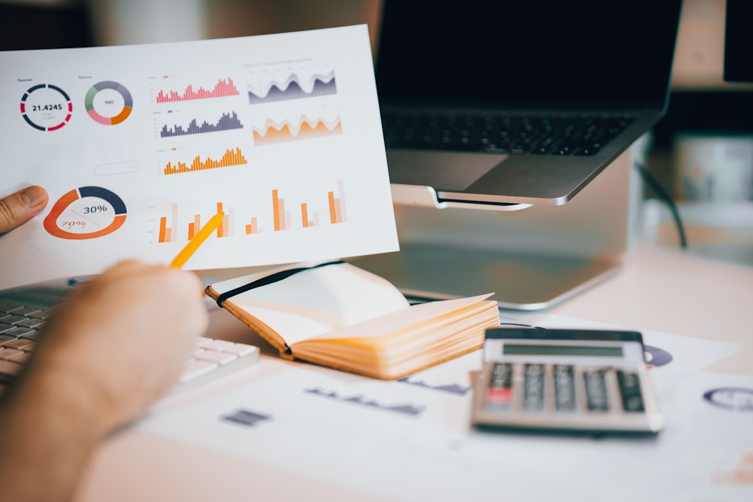 Business owner reviewing financial charts and calculating costs with calculator and laptop on desk. Photo by Unsplash