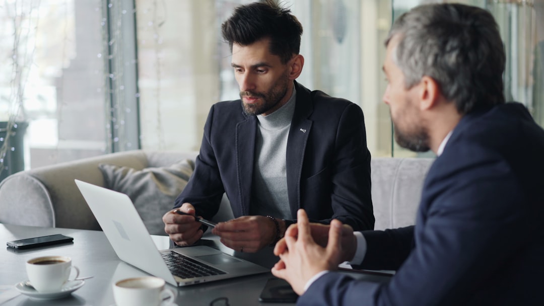 Two business professionals in consultation meeting reviewing SEO strategy on laptop. Photo by Unsplash.